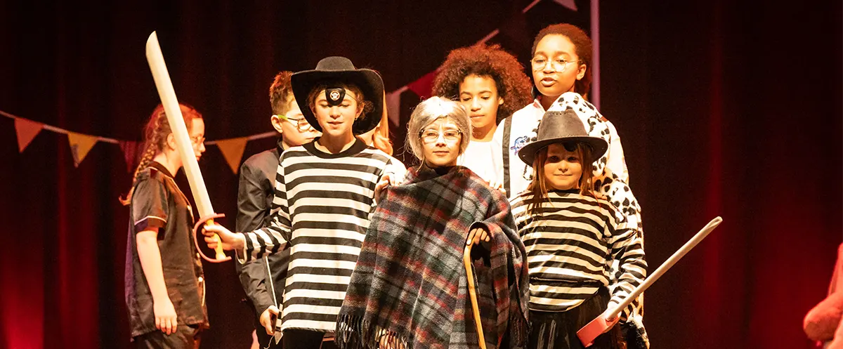 Groupe d'enfants de divers âges sur scène interprétant leurs personnages