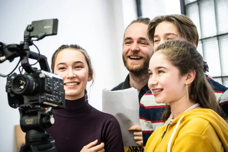 Jeunes visionnant leur scène sur une caméra avec leur professeur