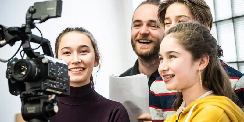 Jeunes visionnant leur scène sur une caméra avec leur professeur